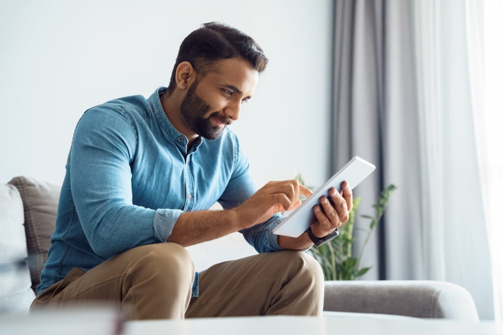 Man sitting on couch, using tablet to review headlines and the q4 market outlook