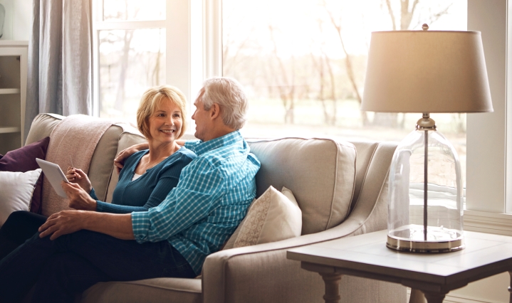 Couple sitting on couch with tablet.