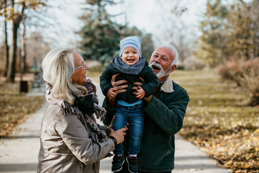 Happy grandparents holding up grandson for a family photo in the park