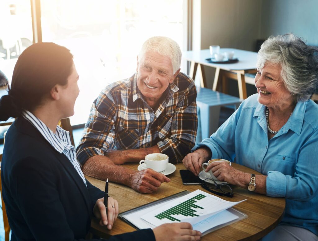 Elderly couple having a coffee-shop meeting with an advisor, reviewing estate planning frequently asked questions