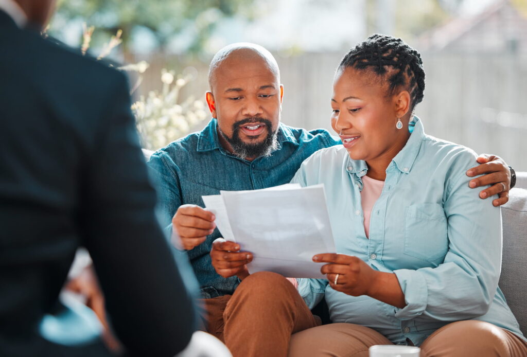 Pre-retiree couple sitting on couch reviewing year-end tax planning checklist across from their advisor