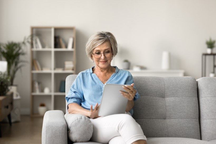 Woman sitting on couch and looking at tablet, reviewing what investors need to know.